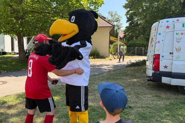 Das Maskottchen begrüßt einen Bewohner.