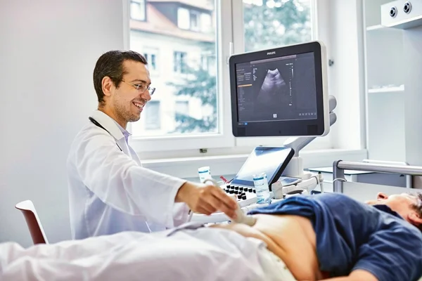 Das Bild zeigt einen Arzt und ein Patienten die gemeinsam in einen Monitor schauen