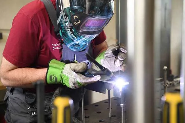 Das Bild zeigt eine Personen die ein Metallstück zusammenschweißt.