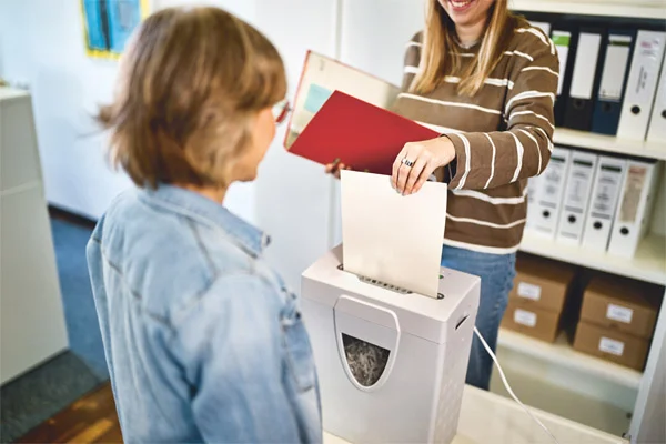Das Gegenüber Zwei Personen stehen an einem Aktenvernichter.