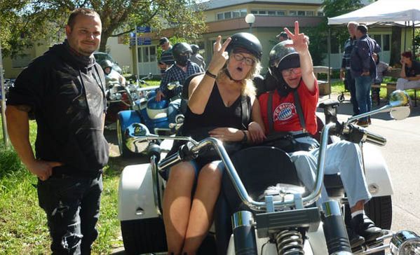 Trike-Fahrt Zwei Personen sitzen auf dem Trike und der Fahrer lächelt in die Kamera.