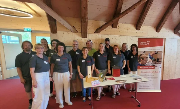 Mehrere Personen tragen das gleiche T-Shirt und stehen hinter einem Tisch.