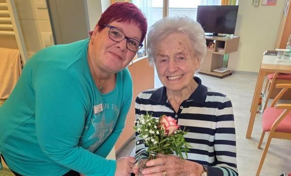 Das Bild zeigt zwei Frauen mit einer Rose