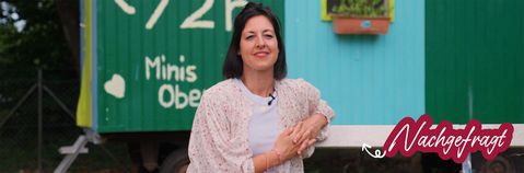 das bild zeigt eine junge frau auf einer bank zum thema nachgefragt: ferienbetreuung. im hintergrund sieht man einen spiel-bauwagen.