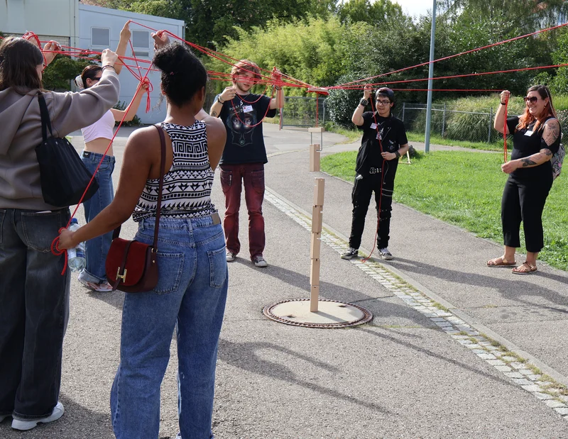 Einführungstag 2026 Eine Gruppe an Personen spielt ein Geschicklichkeitsspiel im Freien.