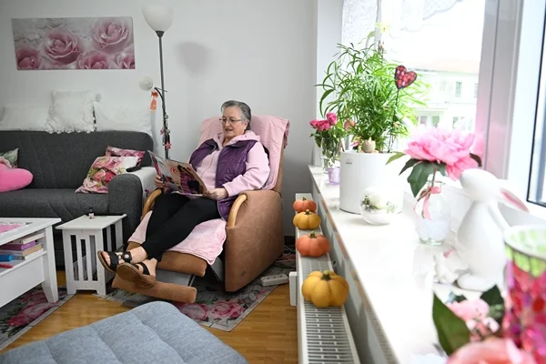 Wohnanlage Berg Das Bild zeigt eine Frau in einem Sessl in einem möblierten Zimmer