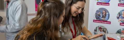 Zwei Frauen schauen auf ein Tablet auf einer Messe.