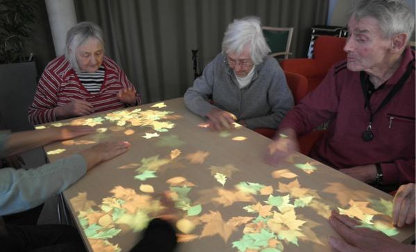 Tovertafel Eine Gruppe älterer Menschen sitzt um einen anprojizierten Tisch