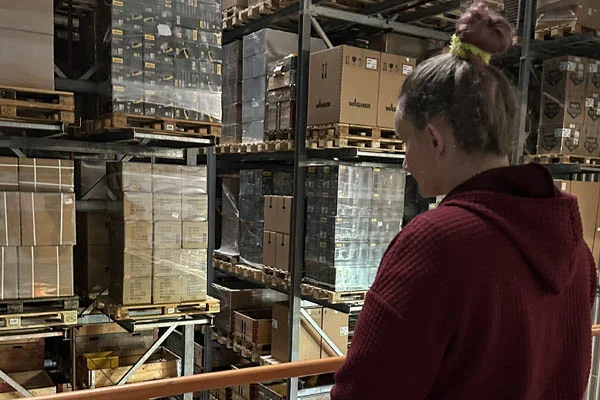 Eine Frau schaut in eine Lagerhalle mit vielen Kartons.
