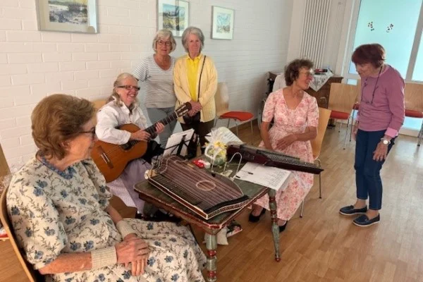 Stubenmusik mit dem Truderinger Saitentrio Das Bild zeigt Musikerinnen und Zuhörerinnen im Gespräch