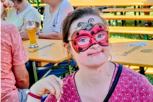 Eine Frau lächelt als Marienkäfer geschminkt in die Kamera.