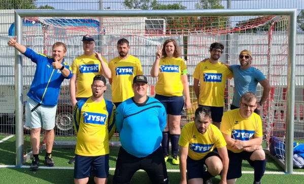 Mehrere Personen mit Behinderungen stehen in Trikots vor einem Fußballtor.
