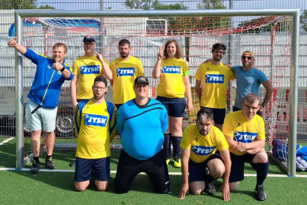 Mehrere Personen mit Behinderungen stehen in Trikots vor einem Fußballtor.