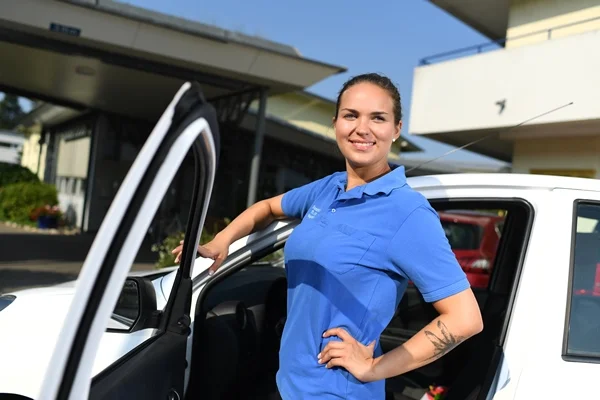 Das Bild zeigt eine Frau vor einer offenen Autotür