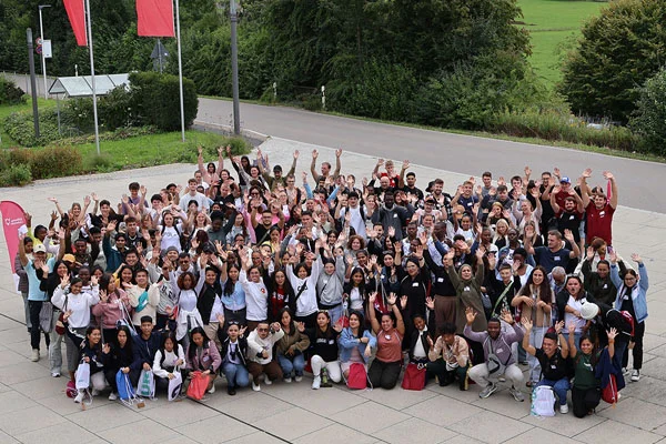 Das Foto zeigt eine große Gruppe winkender, junger Menschen, die mit ihrer Ausbildung beginnen.