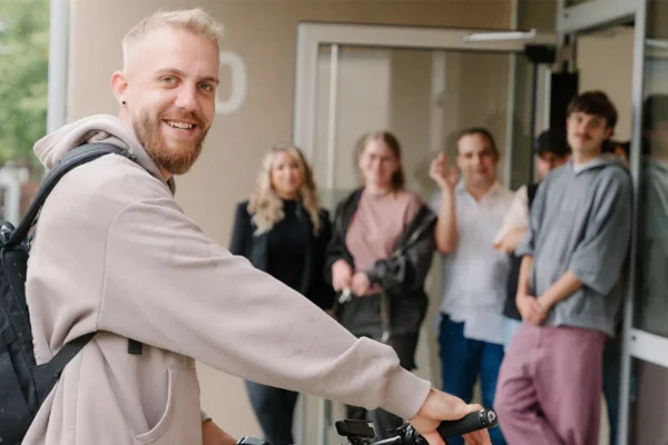 Ein Mann schaut in die Kamera und einige Personen sind im Hintergrund.