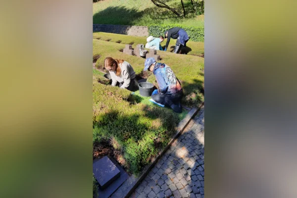 Kriegsgräber Vier Menschen arbeiten auf einem Friedhof.