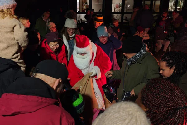 Nikolausfahrt Ein Nikolaus verteilt Geschenke und viele Personen stehen dabei.