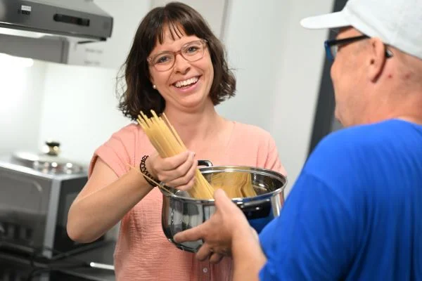 Auf dem Bild sieht man eine Frau und einen Mann die zusammen Spaghetti kochen