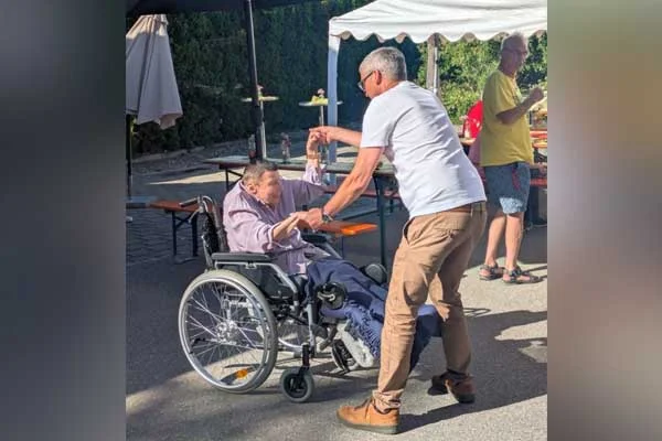 Ein Mann und eine Person im Rollstuhl tanzen.