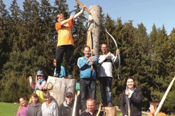 Das Bild zeigt eine Gruppe von Personen die gemeinsam bogenschießen
