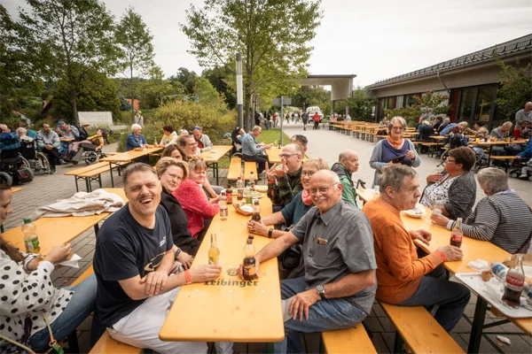 Sommerfest 100 Jahre Rosenharz das bild zeigt eine gruppe von besuchern, die an biertischen sitzt.