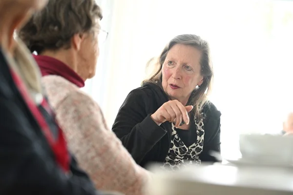 Das Bild zeigt zwei Frauen an einem Tisch im Gespräch