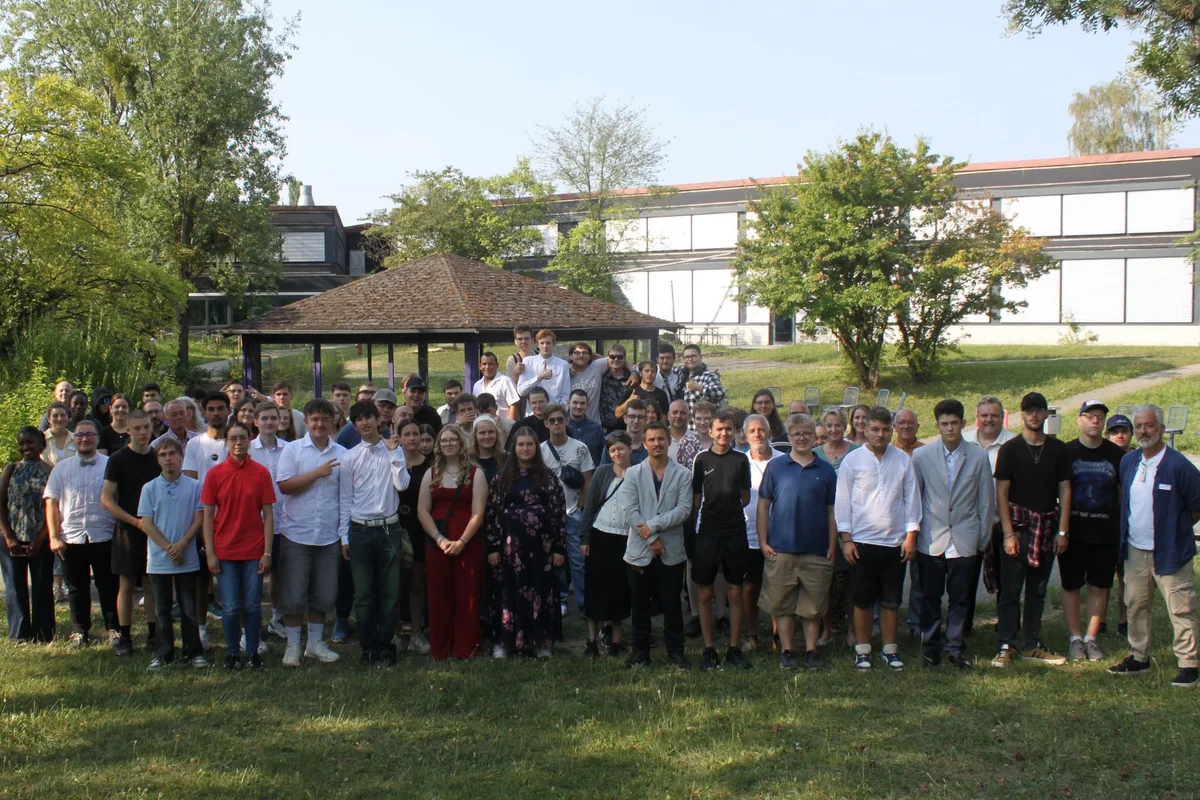 Absolventenfeier Gruppenbild vieler Menschen auf einer Wiese.