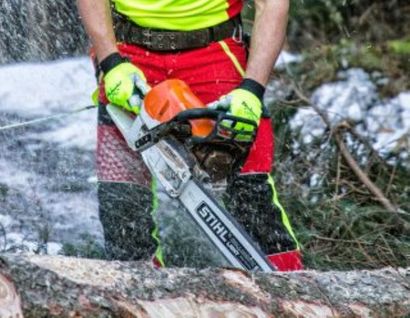 Das Bild zeigt eine Person, die einen Stamm mit einer Kettensäge durchsägt