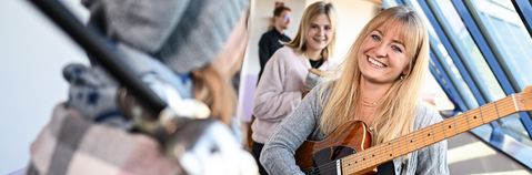 Das Bild zeigt eine junge Frau mit Gitarre