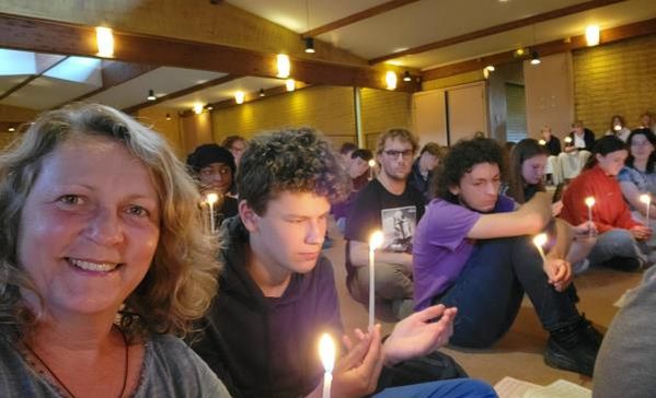 Das Bild zeigt Jugendliche mit Kerzen in einer Halle beim Gottesdienst