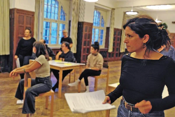 Theaterspiel Eine Frau im Vordergrund und weitere Schauspielerinnen und Schauspieler im Hintergrund.