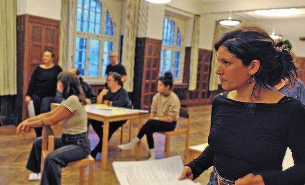 Eine Frau im Vordergrund und weitere Schauspielerinnen und Schauspieler im Hintergrund.