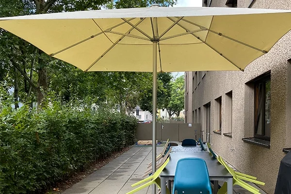 Gemeindeintegriertes Wohnen Ludwigsburg Das Bild zeigt eine Terrasse mit Sitzgelegenheit, einem Sonnenschirm und einer Hecke