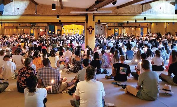 Ein Raum mit vielen sitzenden Personen und Kerzen.