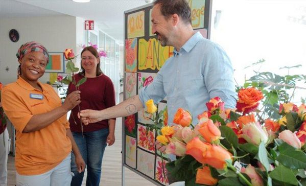 Das Foto zeigt wie der Einrichtungsleiter eine Rose überreicht.