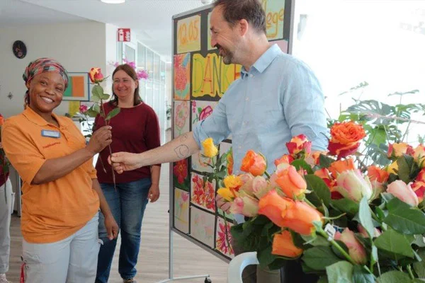 Das Foto zeigt wie der Einrichtungsleiter eine Rose überreicht.