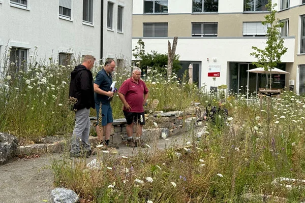 das bild zeigt drei männer, die vor einer blumigen wiese beim haus st. raphael in oberteuringen stehen.