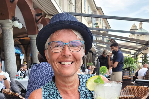 Ein Portraitfoto einer Frau mit Hut, die in die Kamera lächelt.