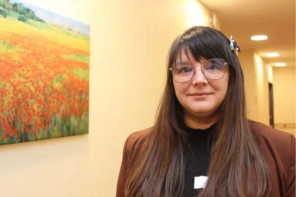 Eine braunhaarige Frau schaut in die Kamera und lächelt.