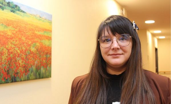 Eine braunhaarige Frau schaut in die Kamera und lächelt.