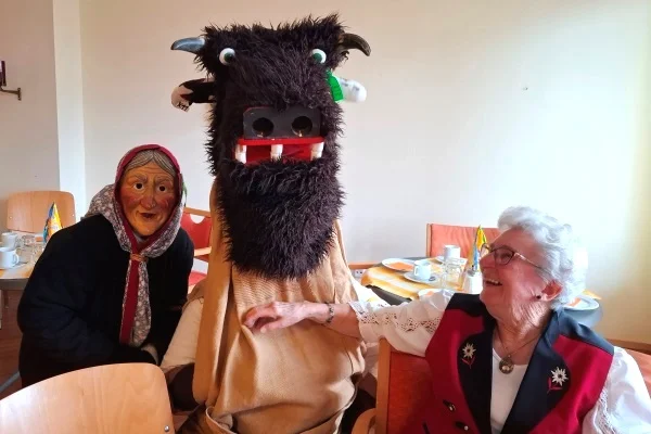 Das Bild zeigt eine Frau mit zwei Menschen in Fasnetkostümen