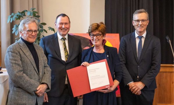 Drei Männer und eine Frau lächeln in die kamera