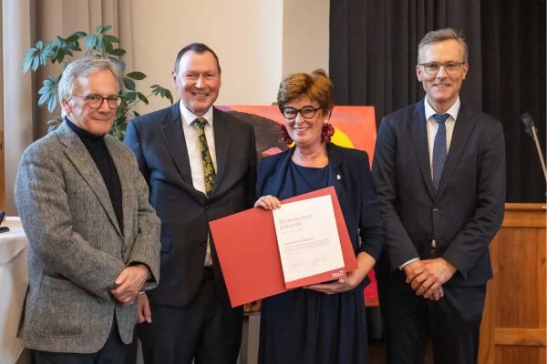 Drei Männer und eine Frau lächeln in die kamera