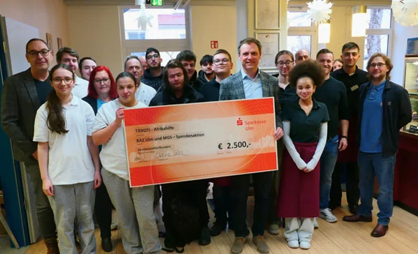 Eine Gruppe Schülerinnen und Schüler hält einen Spendenscheck.