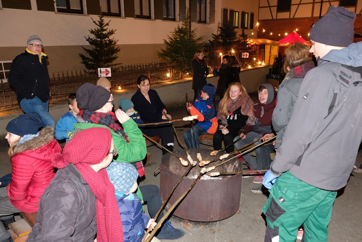 Das Bild zeigt Besucher beim Stockbrot grillen