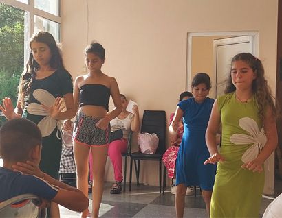 Vier Kinder und Jugendliche führen einen Tanz vor.