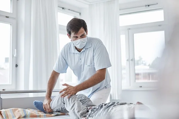 Das Bild zeigt einen Arzt der gerade eine Behandlung an einem Patienten durchführt