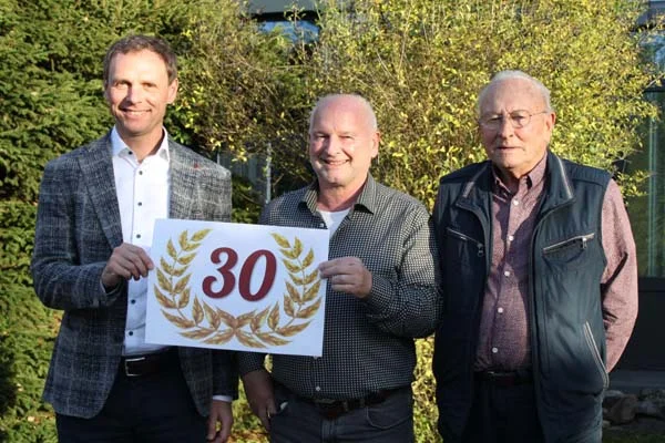 Gruppenbild von drei Männern mit einem Schild "30".