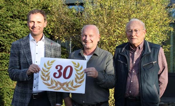 Gruppenbild von drei Männern mit einem Schild "30".